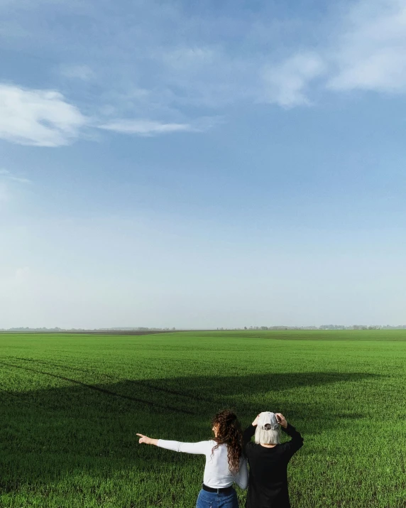 two people in a green field flying a kite