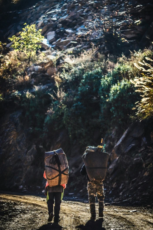 two men walking down a trail holding backpacks