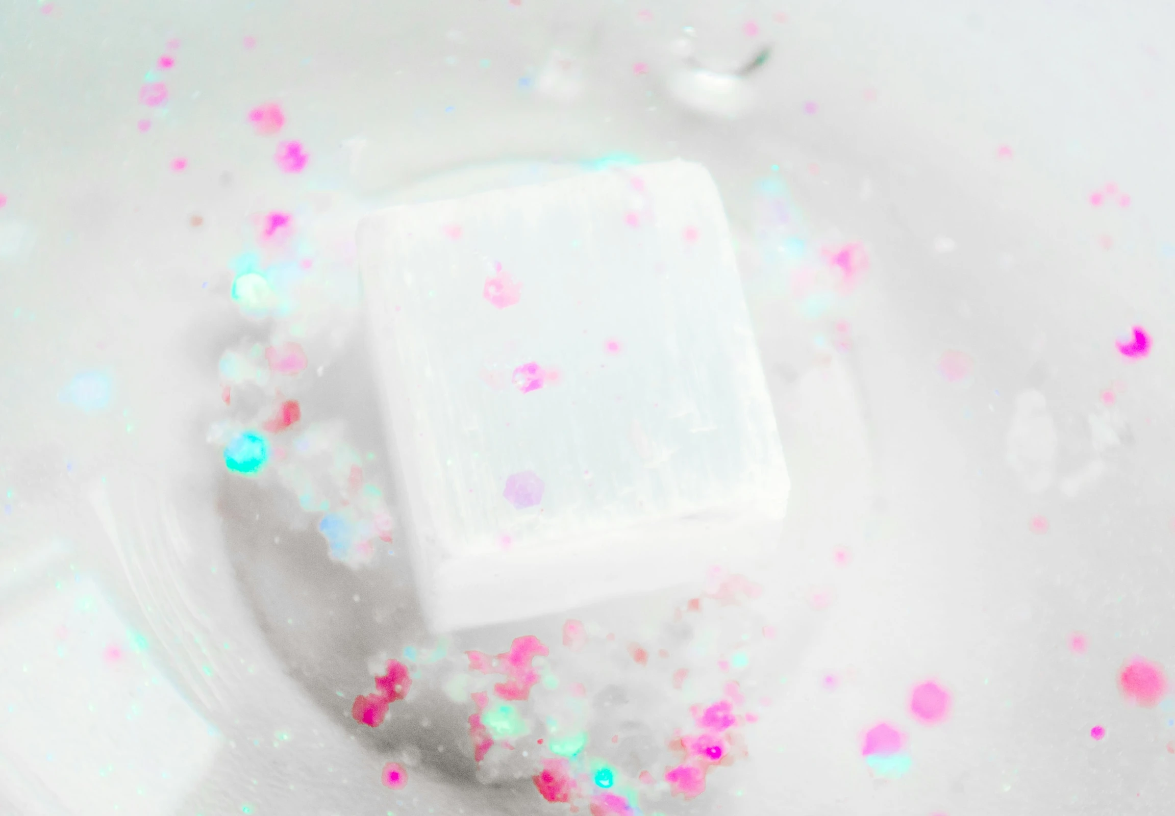 a soap bar surrounded by flecks of pink, blue, and green glitter