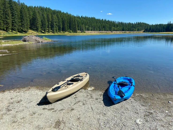 two kayaks sitting by the shore of the lake