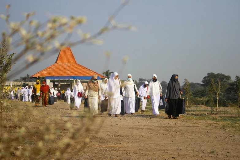 people walking together in a line on dirt ground