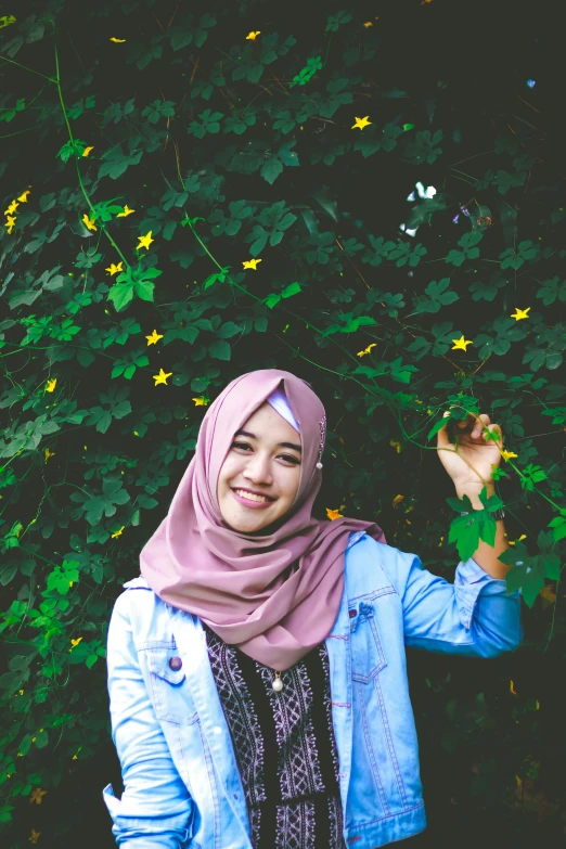 an image of a girl with a hijab that is holding onto some plants