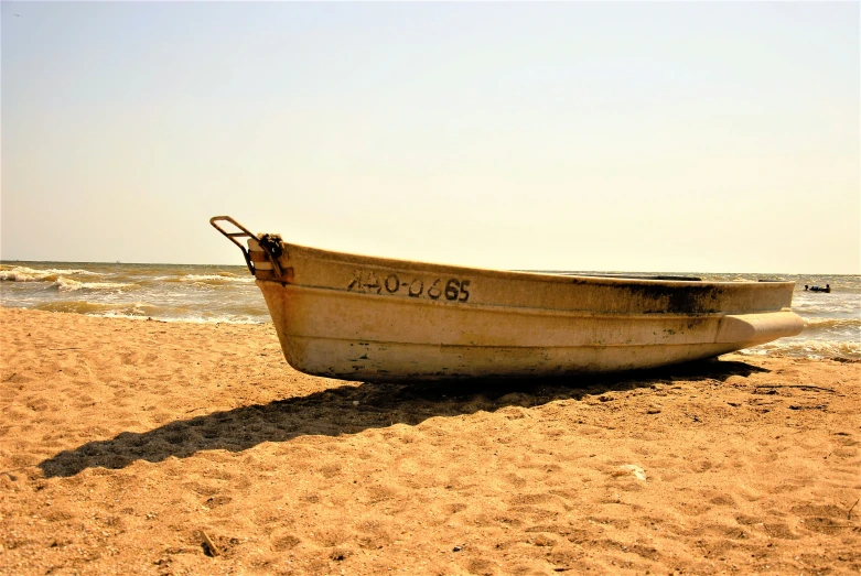 a boat sits on the beach with footprints around it