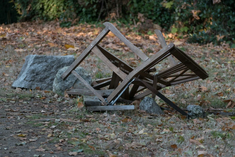 an empty wooden chair on the ground with it's broken off