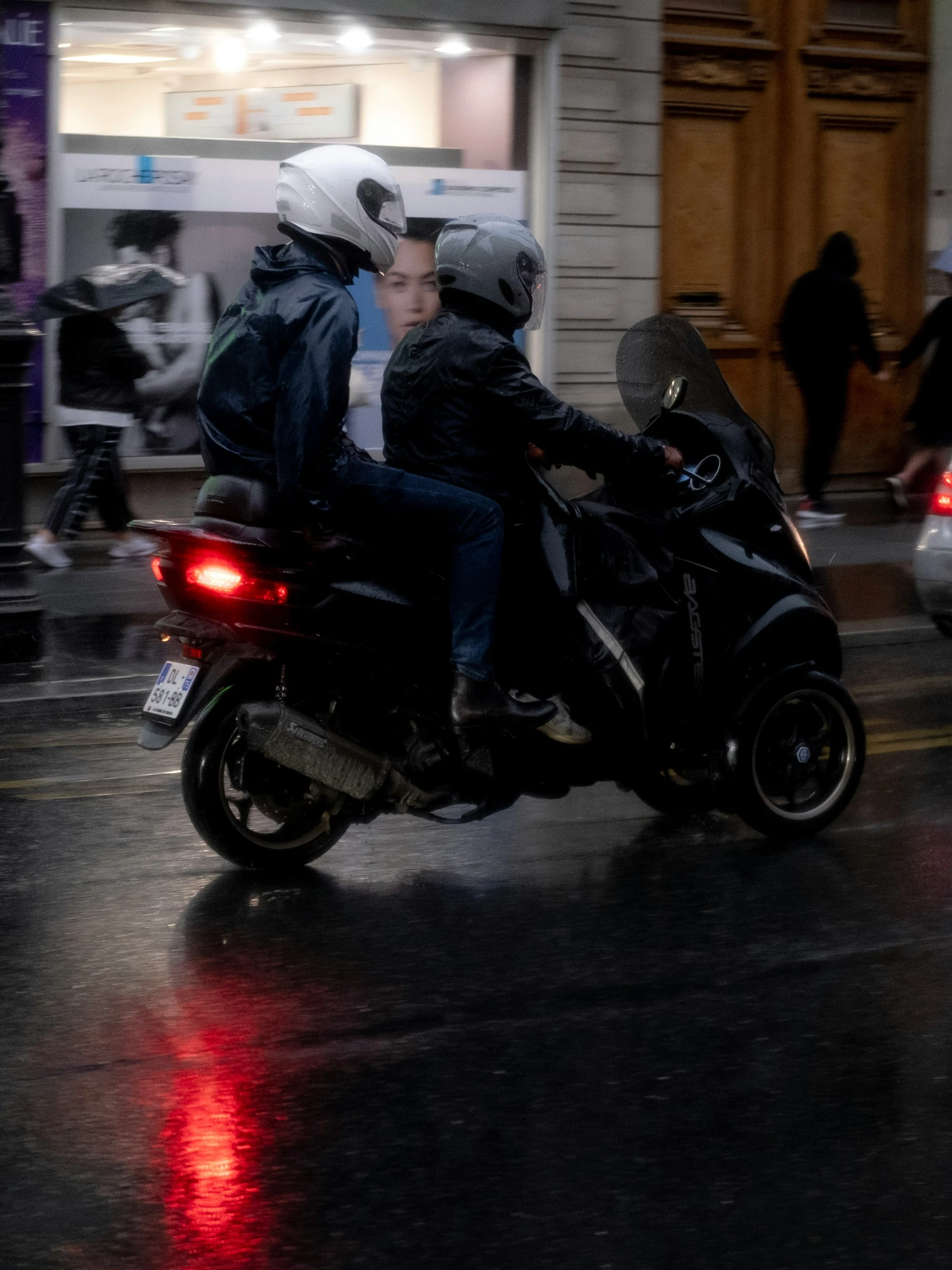 two people on a motorcycle driving in the rain