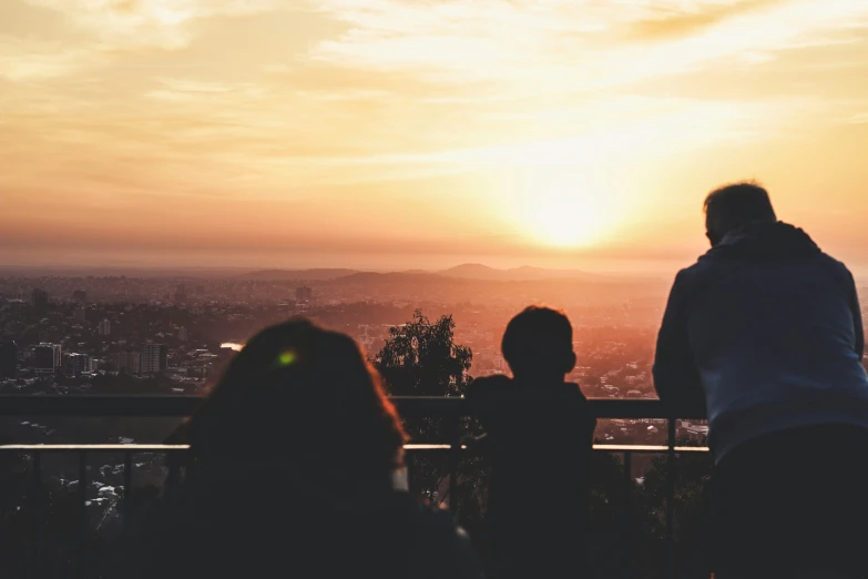 two people and a child looking at the sun setting