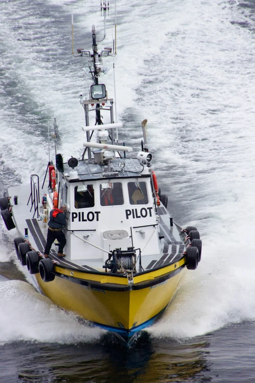 a pilot on a yellow and white boat in rough water