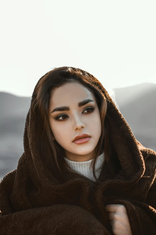 a woman is covering herself with a brown blanket