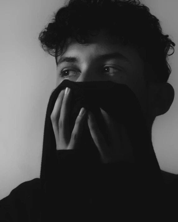 a black and white po of a man covering his face with his hands