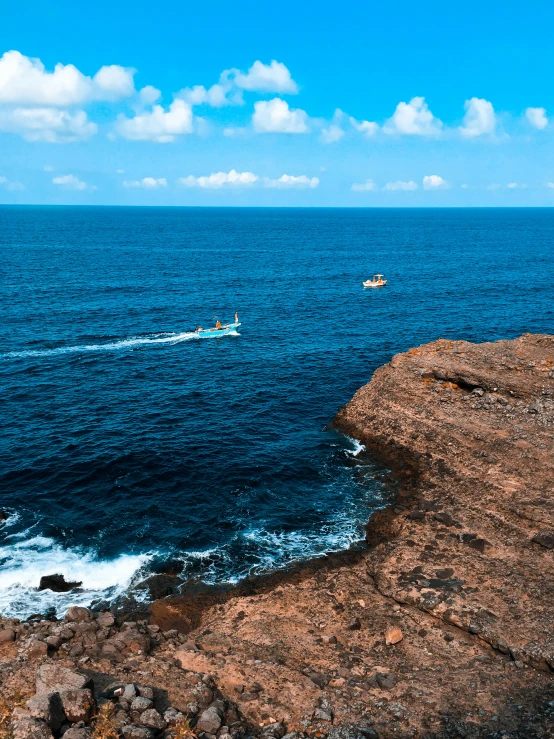 a small boat is sailing by some rocky coast