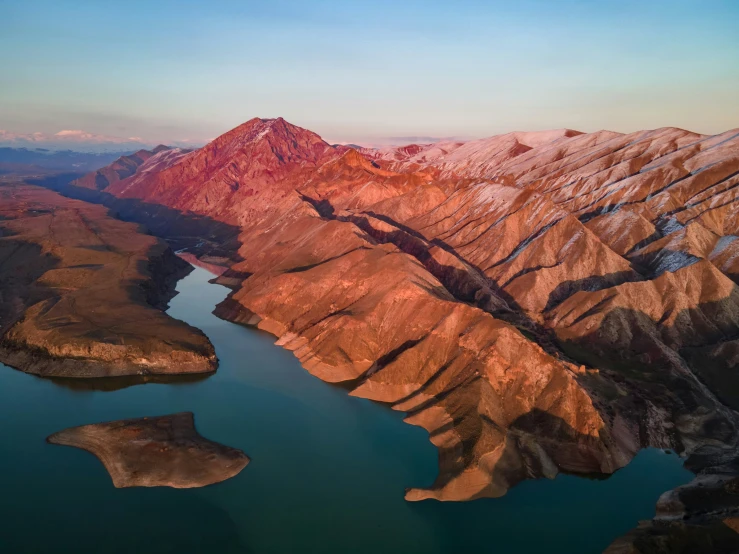 a mountain with many different sides next to water