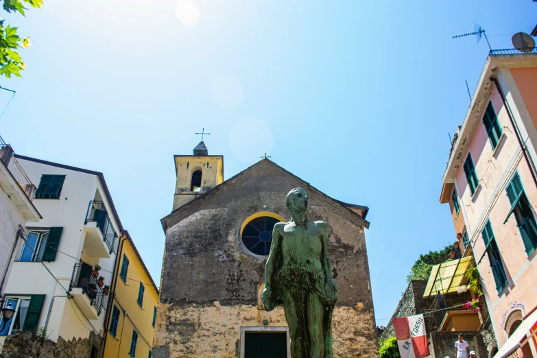 the statue is green and has a tower in the background