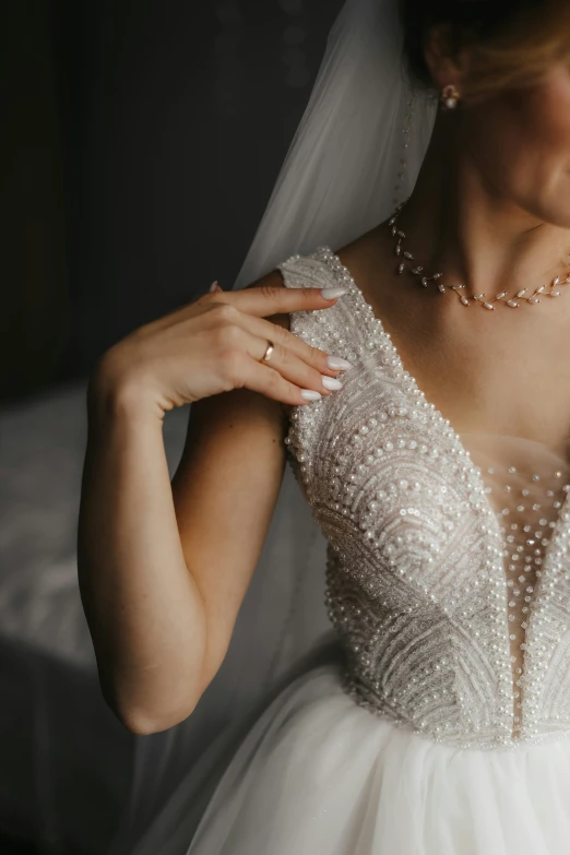 the bride wears a beaded white veil and a diamond necklace