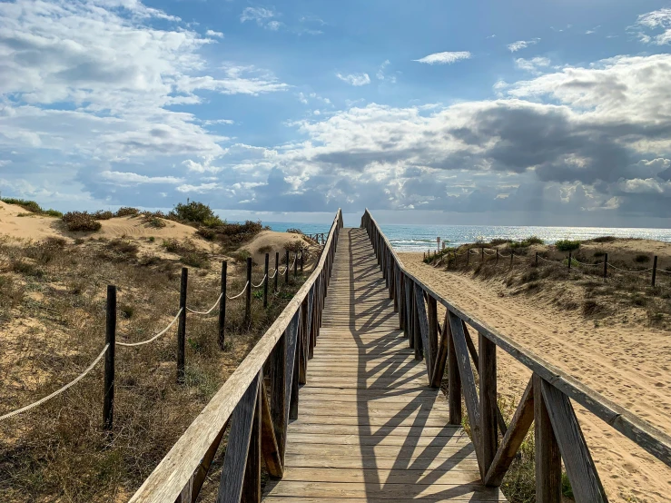 there is a long wooden path leading to the beach