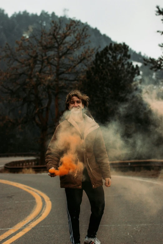 a man skateboarding down a road with orange smoke in the air