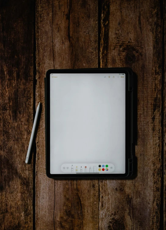 a tablet and pen on a wooden table