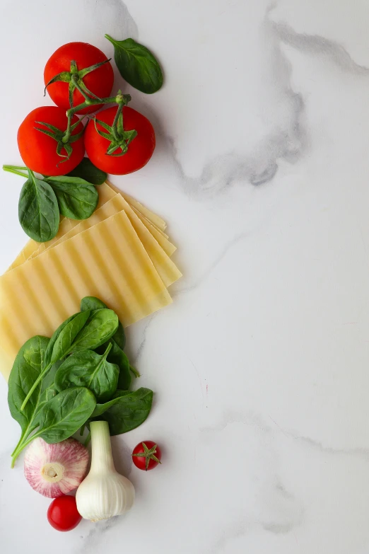 various vegetables and cheeses displayed on a white surface