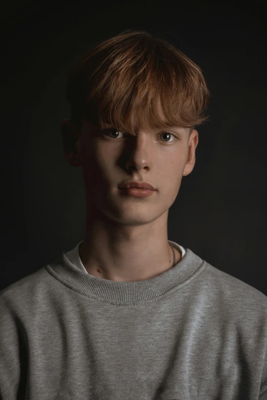 man with brown hair posing for a po in a gray shirt