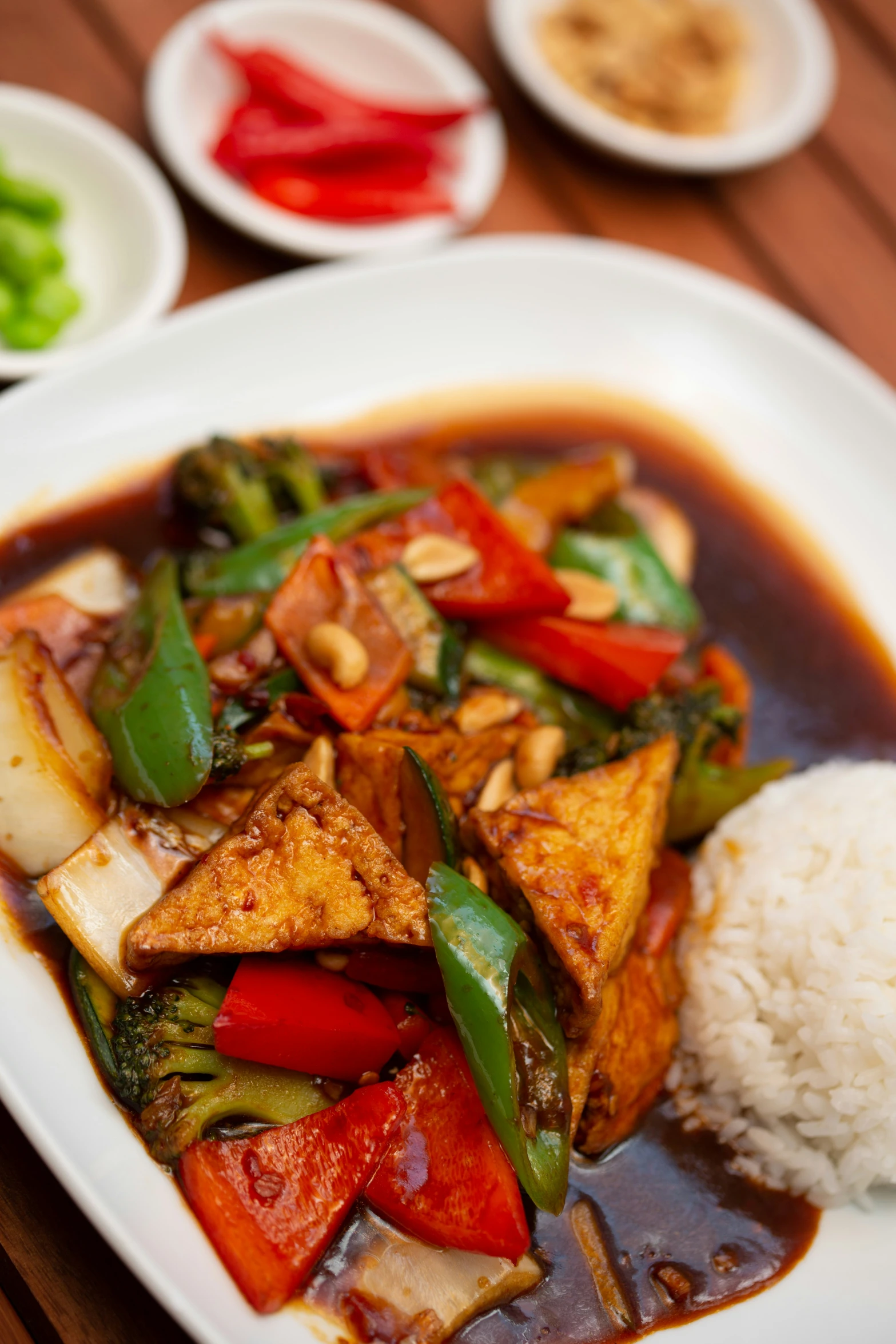 some red bell peppers tofu with rice and sauce on a plate