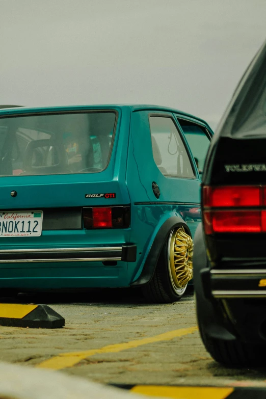 an antique green car is parked behind other vehicles