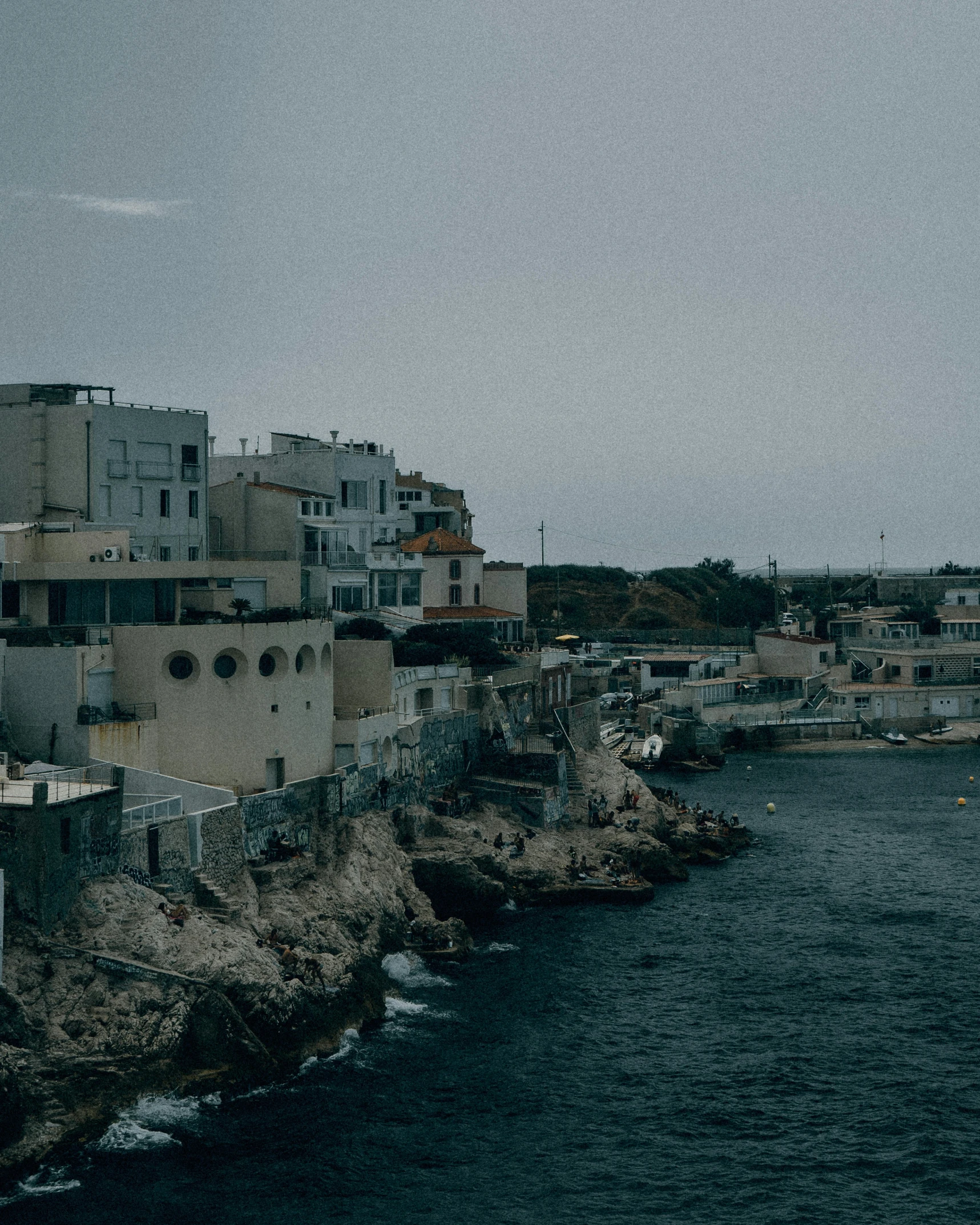 several people in boats on the ocean near some buildings