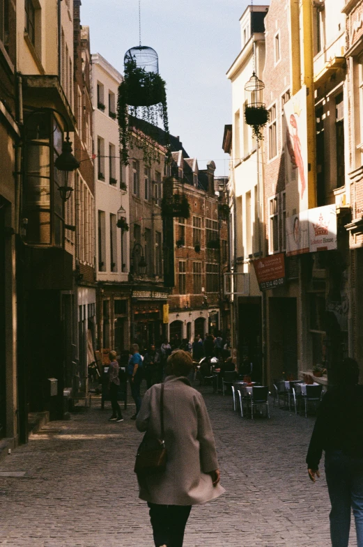 a woman walking down a street between tall buildings