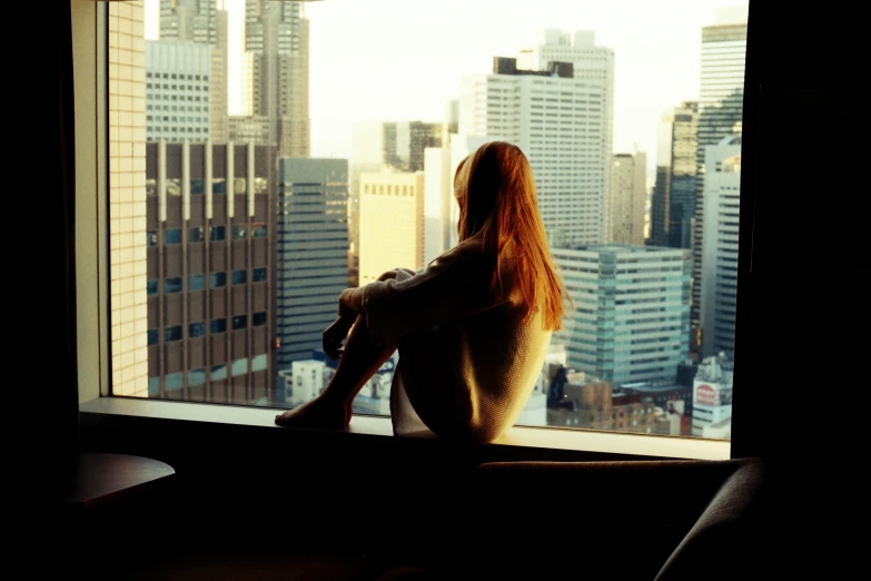 a woman sitting in a window sill looking out