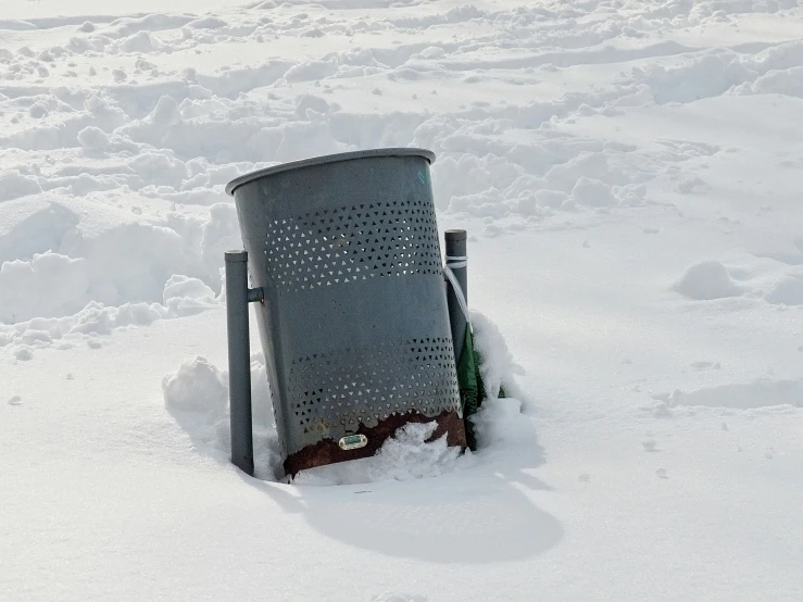 a garbage can buried in snow in a field