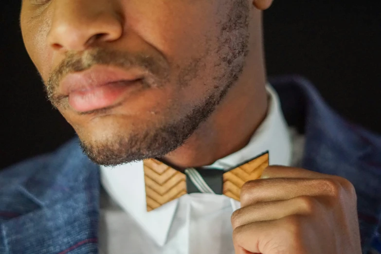 a man with dark skin wearing a suit and a bow tie