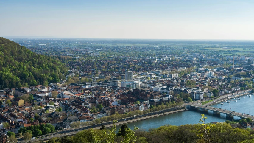 a city next to water with trees and mountains around