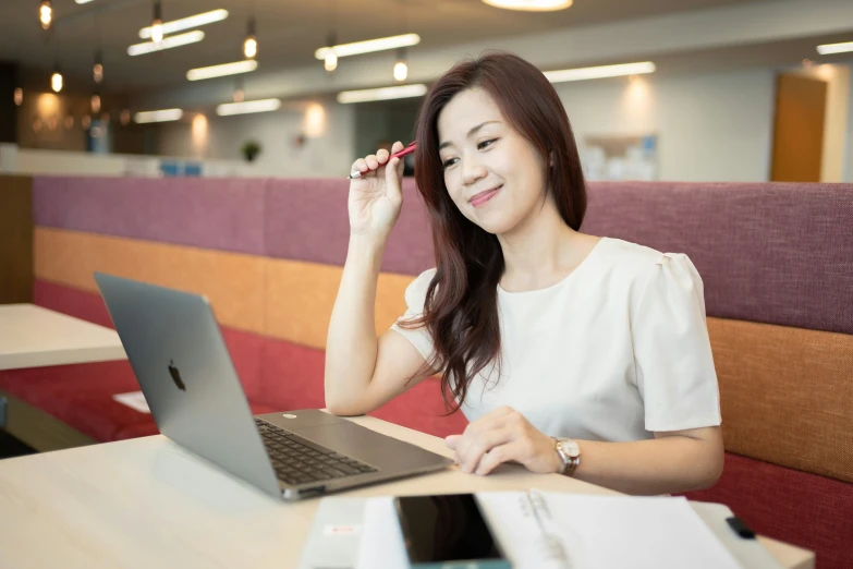 a woman sitting at a table with her laptop and a pen