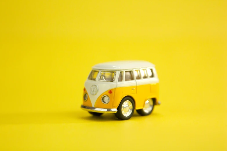 an old yellow and white van with grey roof parked on a plain yellow background