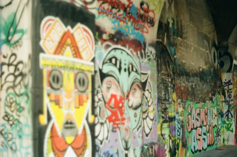 a wall with many colorful graffiti and spray paint on it