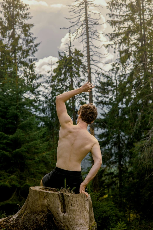 a man standing on a large piece of tree trunk, with his arms in the air