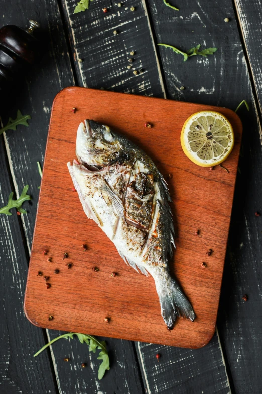 an image of a fish with lemon slices on a  board