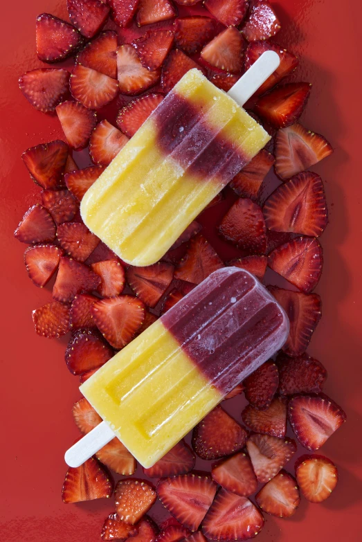 two popsicles with chocolate on top are surrounded by strawberries