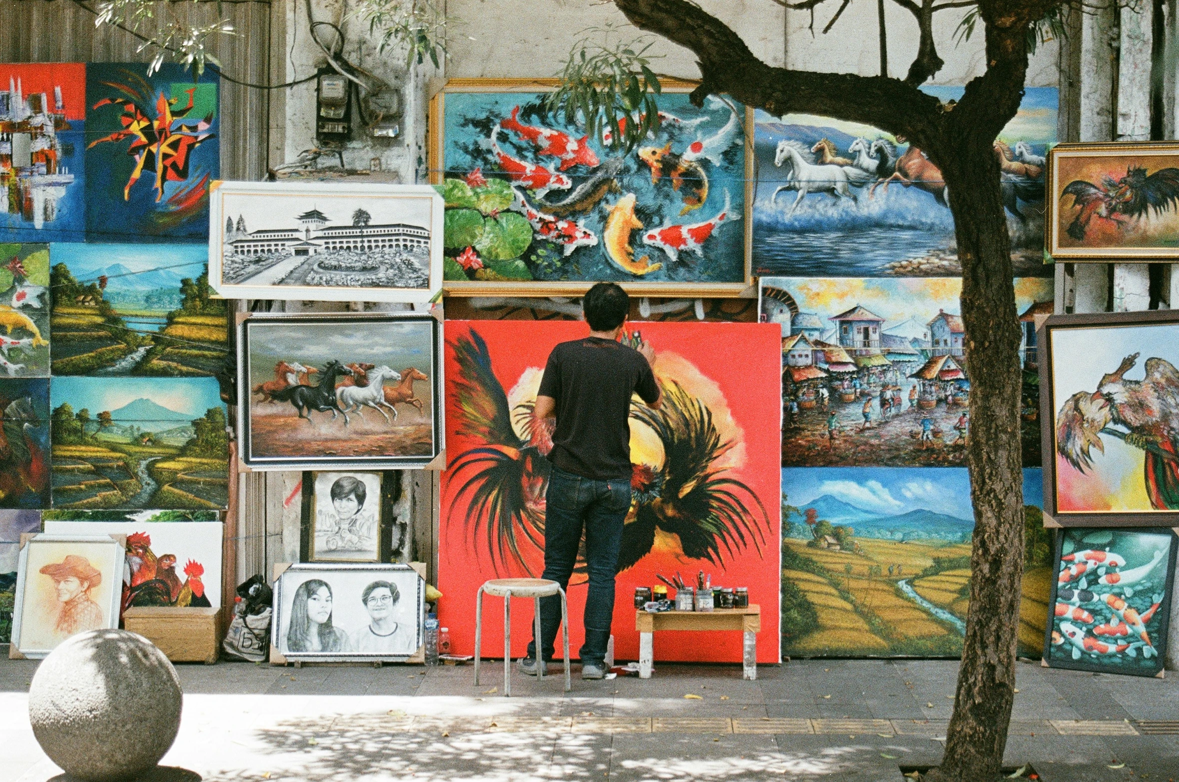 a man looking at art on display next to a tree