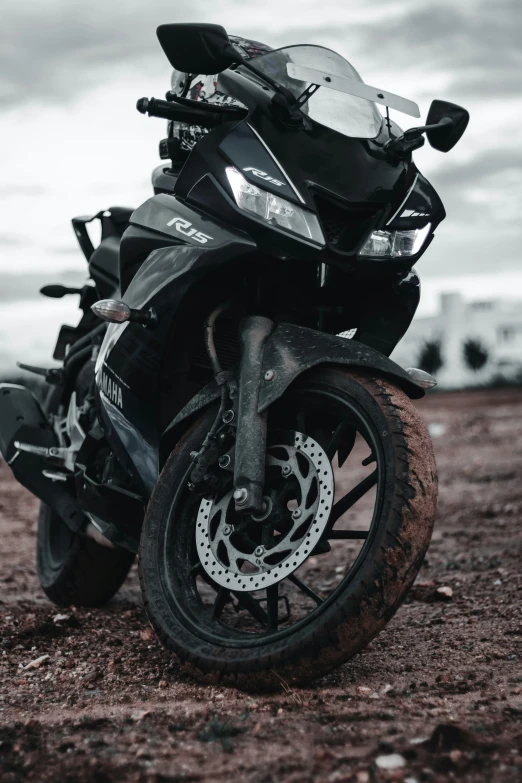 a motorcycle parked on some dirt with a cloudy sky