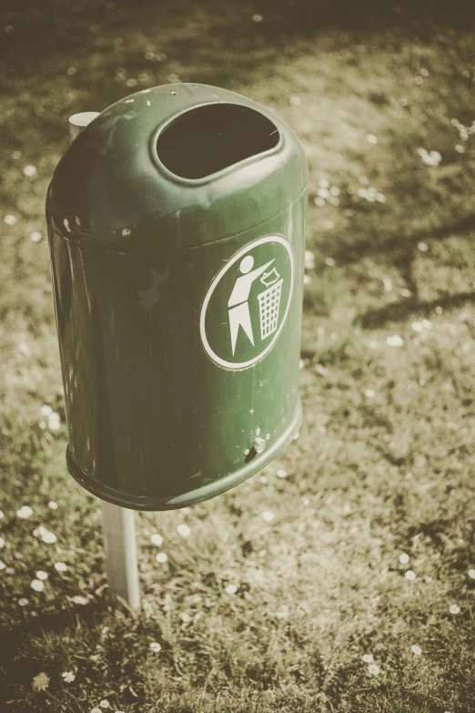 a green trash can sitting in the grass