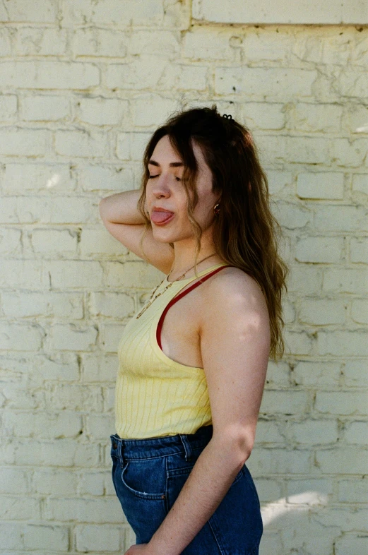 a woman holding onto her hair and leaning against a wall