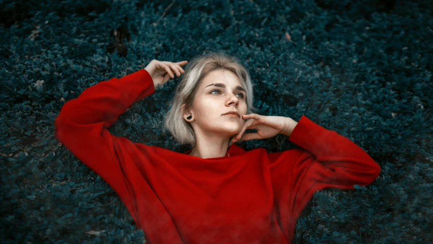 a woman in a red sweater resting against a black background