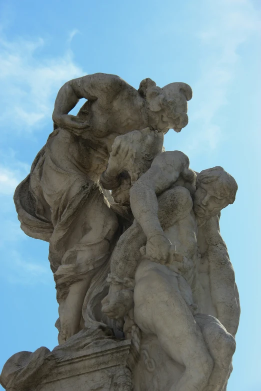 a statue with three people is against a blue sky