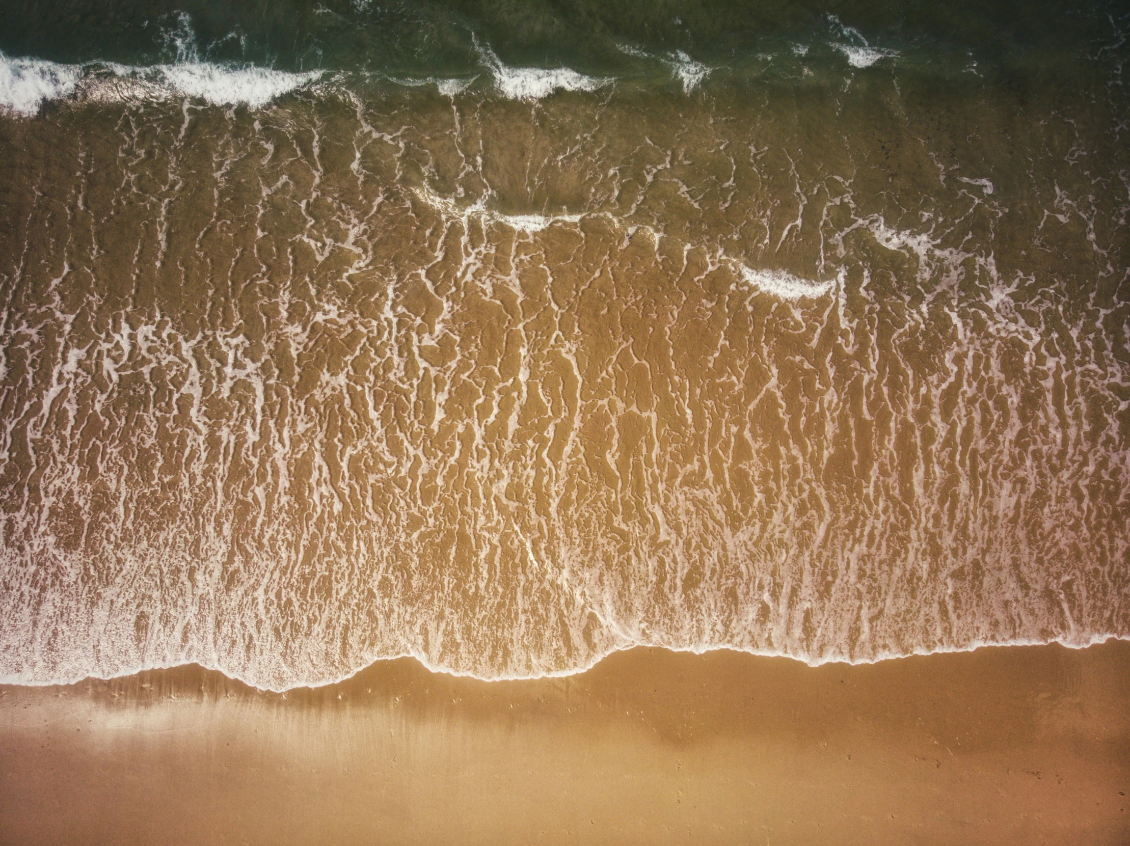 waves rolling in to shore from above the sand