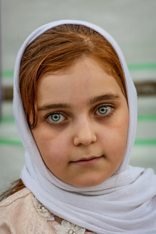 a woman with blue eyes is wearing a headscarf