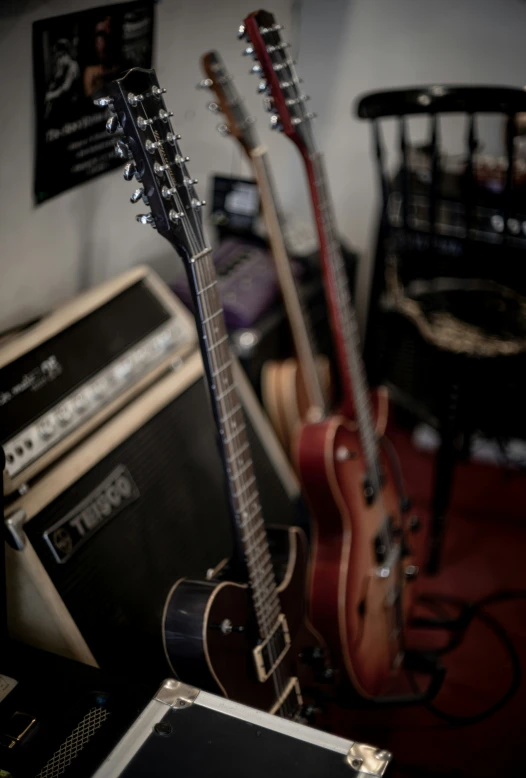 three guitars are sitting on a table near other equipment