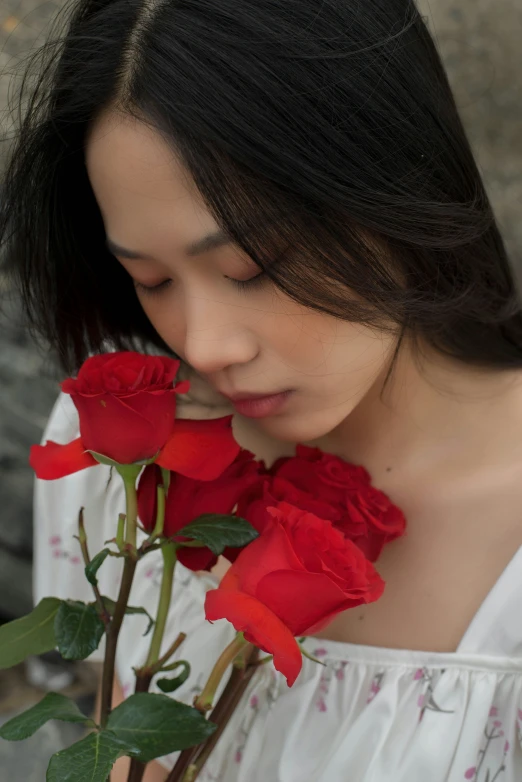 a woman holding roses against her neck, with her eyes closed