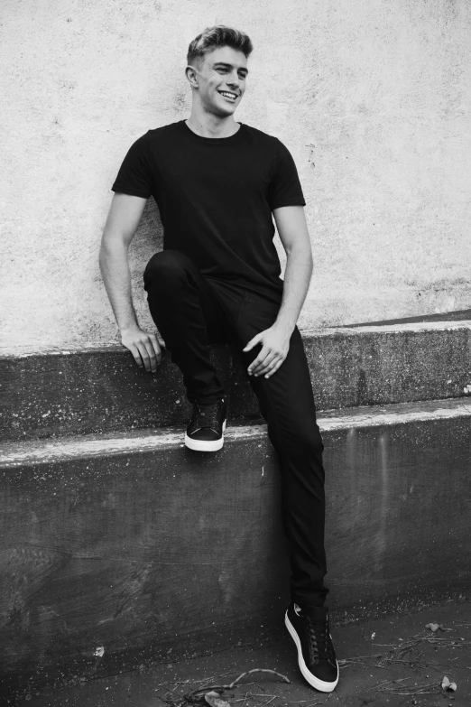 black and white image of a man sitting against the wall