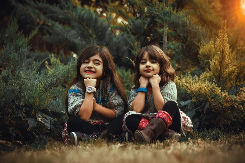 two girls sit side by side in the woods