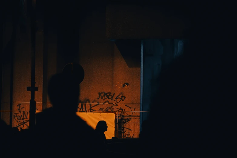 silhouetted person in dark area with wall and door with graffiti