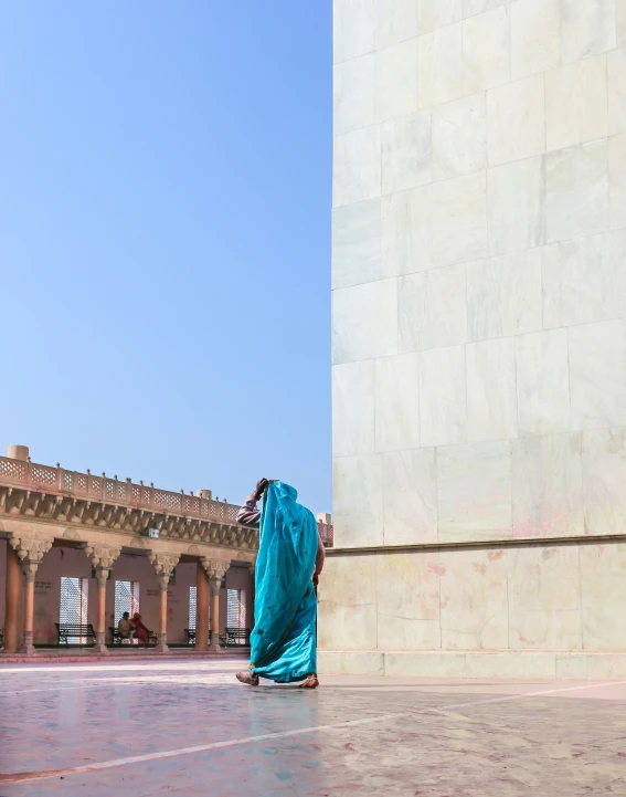 a person wearing a blue sari standing in front of a building